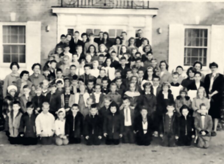 Whole-school portrait of students and teachers in front of the church hall, 1963